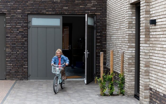 Meisje fietst uit openslaande garagedeur